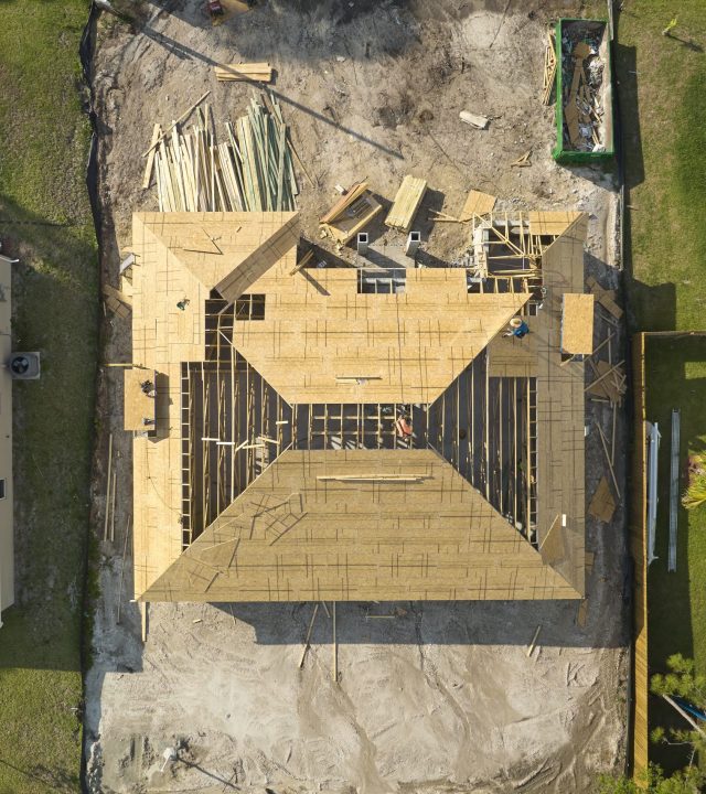 aerial view of suburban private house wit wooden roof frame under construction in florida quiet rural area